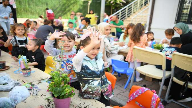 Aileler ve çocuklar, birlikte saksı boyayıp çiçek ekti